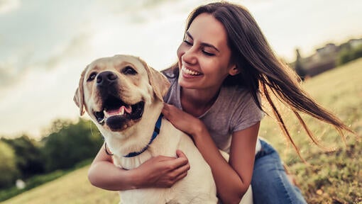 woman hugging her lab in the park